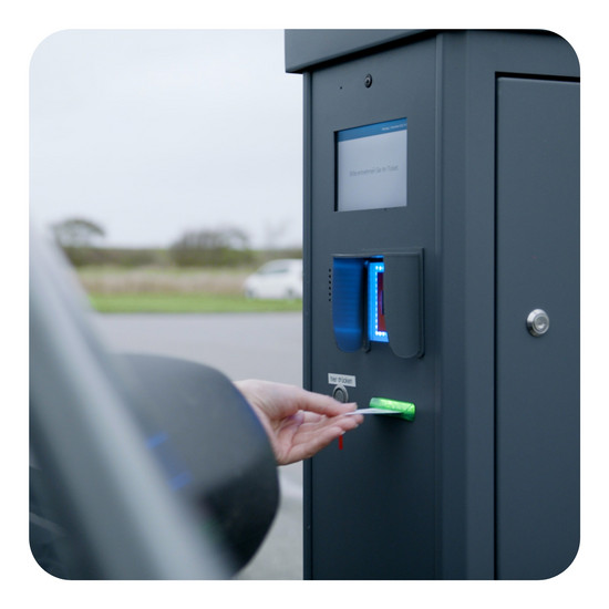 Eine Person steckt eine Karte in einen Fahrkartenautomat