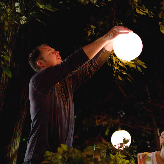 Ein Mann hängt eine runde Leuchte auf