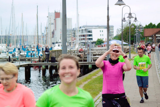 Eine Marathonläuferin zeigt ein Herz in die Kamera