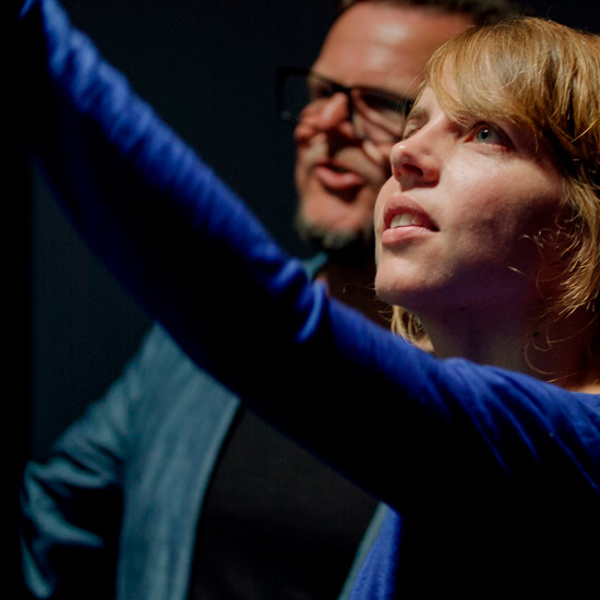 Eine Frau und ein Mann blicken auf etwas, vielleicht eine Tafel oder Pinnwand. 