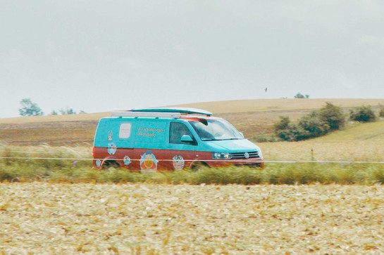 Ein blau roter VW Bus fährt auf dem Land
