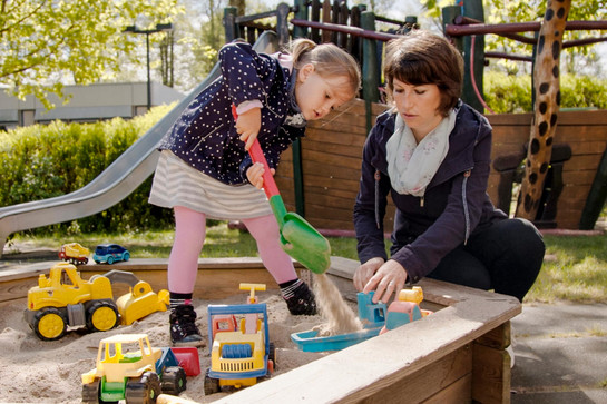 Mutter und Kind spielen im Spielkasten
