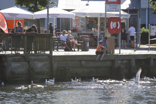 Ein Kind sitzt am Flensburger Hafen