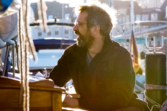 Joachim Freitag sitzt auf einem Segelboot am Flensburger Hafen