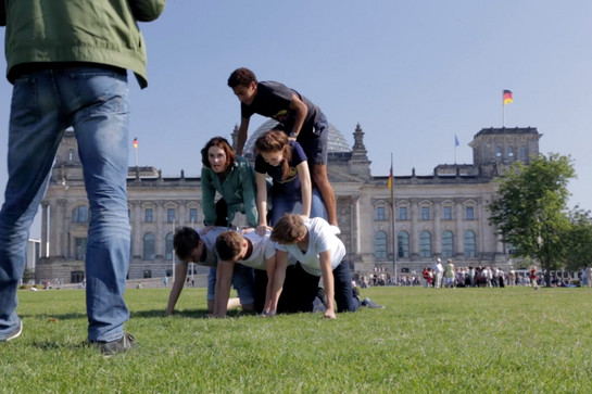 Fünf Jugendliche machen eine Pyramide vor dem deutschen Bundestag