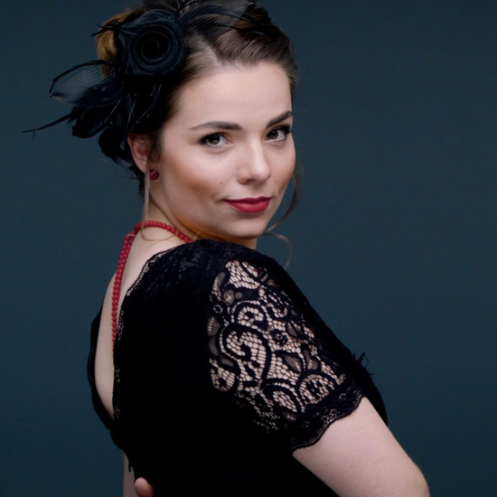 Eine junge Frau im schwarzen Spitzenkleid posiert vor der Kamera