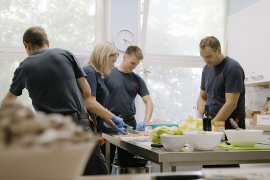 Vier Feuerwehrmänner bereiten essen zu