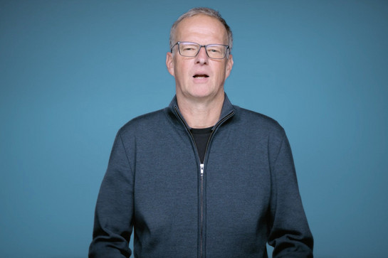 Ein Mann mit grauer Brille spricht in die Kamera