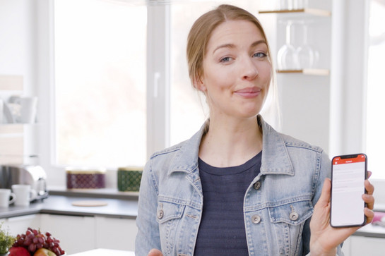 Eine blonde Frau hält ihr Handy in die Kamera