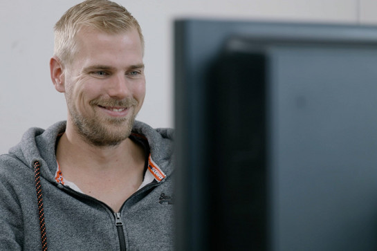 Ein blonder Märtens Mitarbeiter lächelt auf den Computer Bildschirm