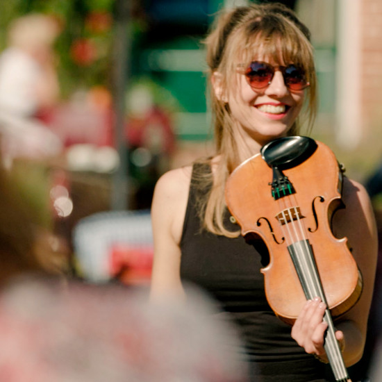 Eine Frau mit Sonnenbrille spielt auf einer Geige
