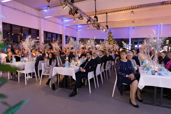 Veranstaltungssaal mit Gästen an langen Tafeln
