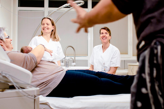 Eine Frau liegt auf einem Krankenbett und hält ein Baby im Arm