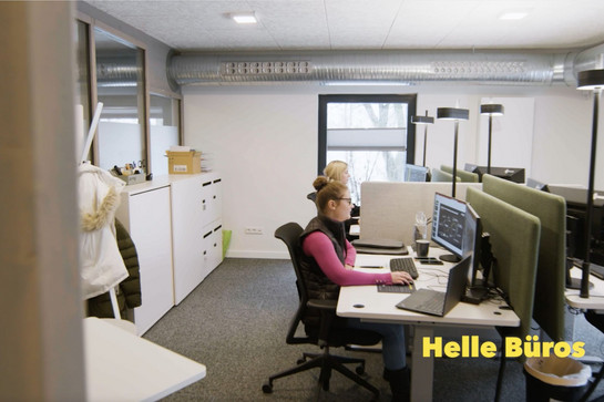 Zwei Frauen sitzen nebeneinander an je einem Schreibtisch und arbeiten