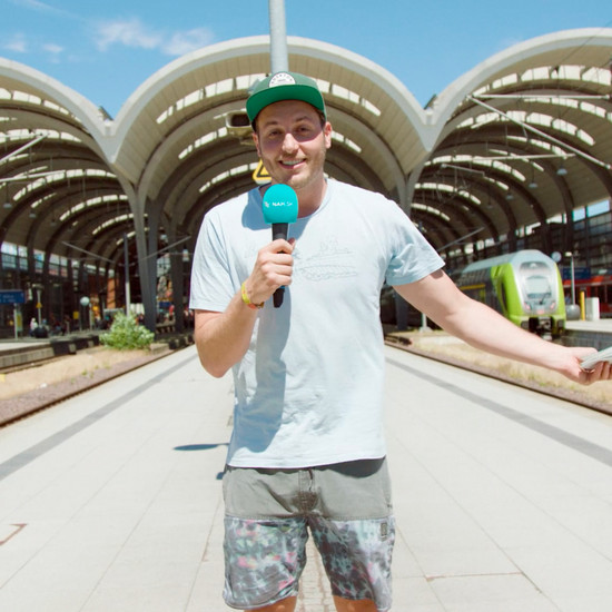 Sommerferienticket Lars steht auf einem sonnigen Bahnstieg