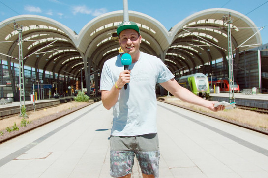 Lars steht auf einem sonnigen Bahnstieg