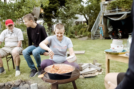 Anna Bandholt bereitet essen in einer Feuerschale zu