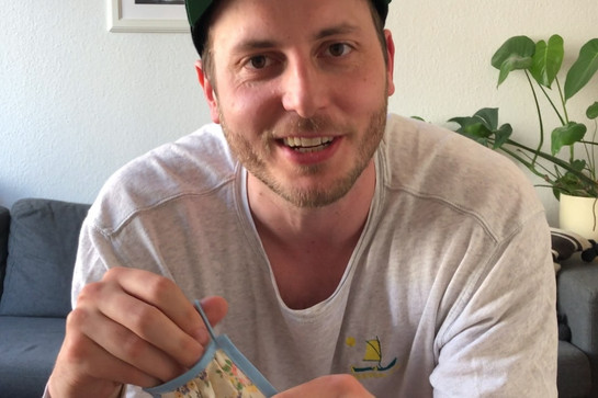 Lars hält eine geblümte Maske in der Hand