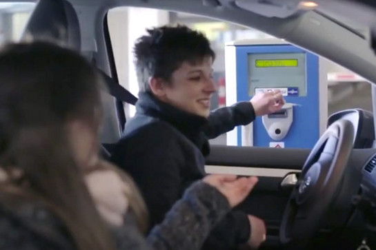Eine Frau steckt ein Parkticket in einen Automaten