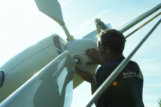 Ein Easywind Mitarbeiter montiert ein weißes Windrad