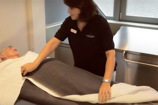 Syltness Mitarbeiterin wickelt eine Decke um einen Gast
