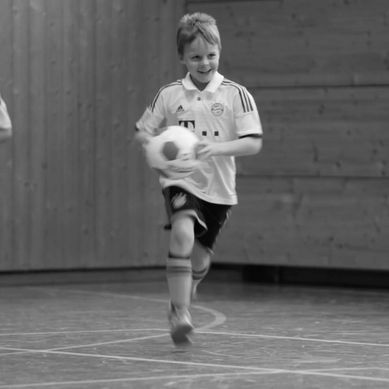 Ein Kind läuft mit einem Fußball in der Hand