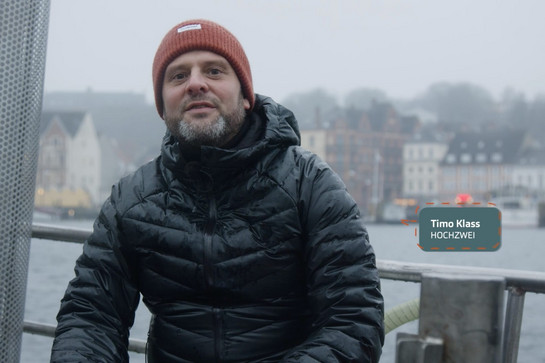 Timo Klass sitzt bei Regen auf einem Schiff