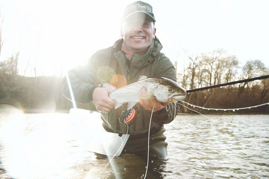 Ein Angler hält einen Fisch in die Kamera
