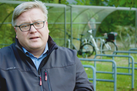 Ein Mann mit einer schwarzen Windjacke im Interview