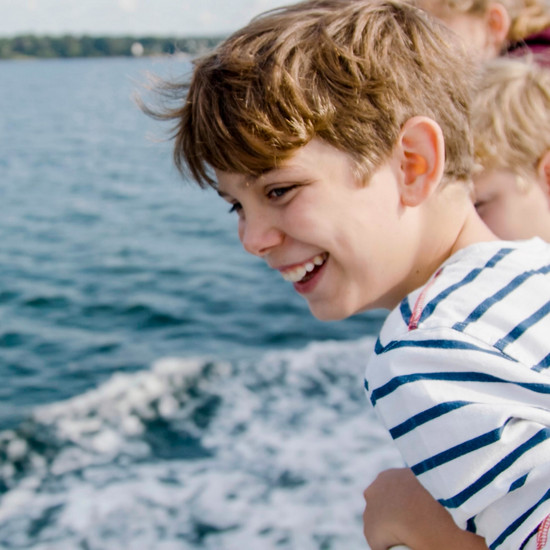 Ein Kind im gestreiften Shirt guckt auf das Meer