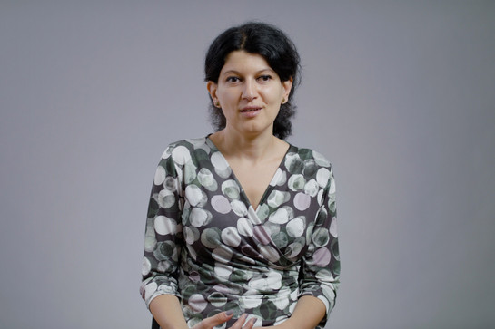 Eine Frau mit schwarzen Haaren und grauen Kleid