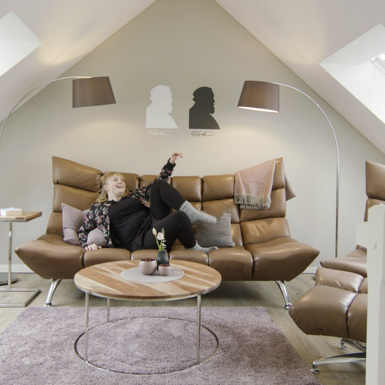 Eine blonde Frau liegt in einem braunen Sofa