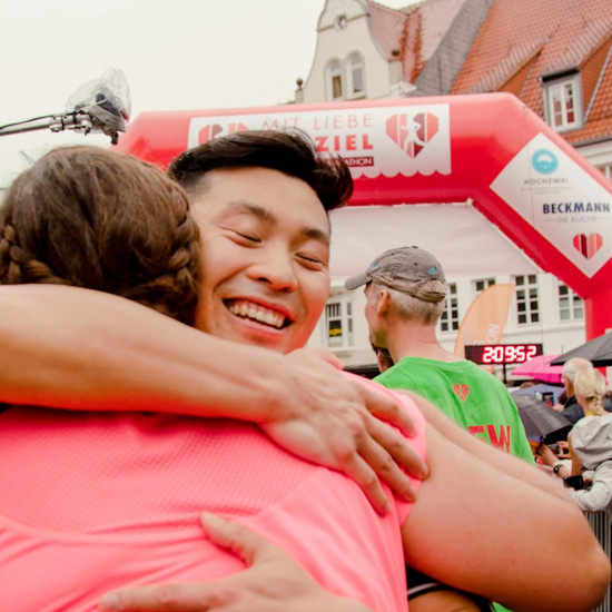 Ein Marathon Läufer umarmt eine andere Marathon Läuferin