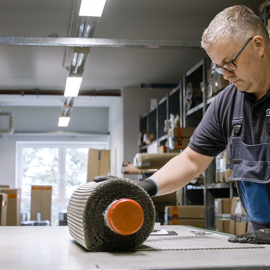 Ein Märtens Mitarbeiter rollt ein metallisches Fließband aus