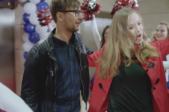 Eine Frau in roter Jacke jubelt mit Cheerleadern