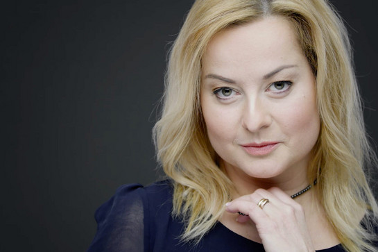 Eine blonde Frau spielt mit ihrer Kette