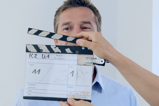 Eine Person hält eine Filmklappe vor einem Mann