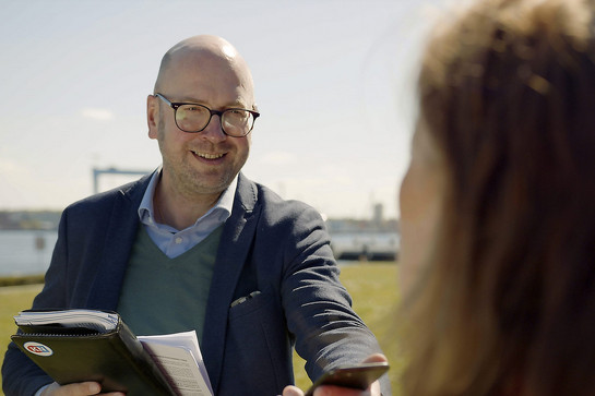 Lächelnder Mann mit Brille mit KN-Mappe 
