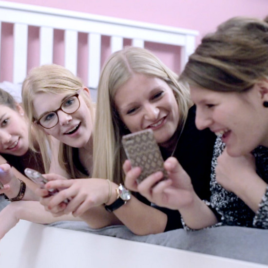 Vier Mädchen liegen auf dem Bett und gucken auf ihre Handys