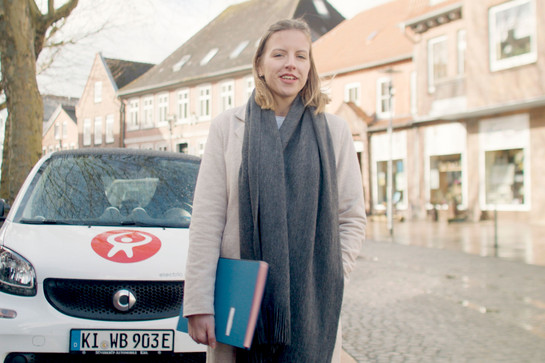 Eine Frau steht auf einem Gehweg mit Akten unter ihrem Arm