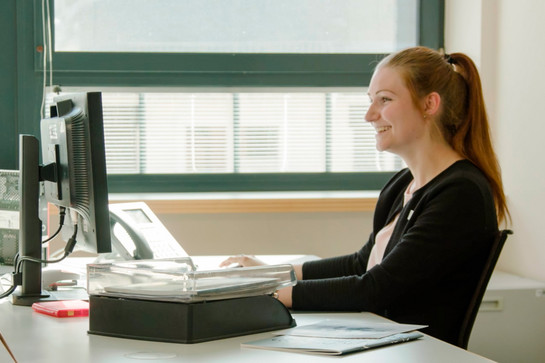 Eine Nospa Mitarbeiterin sitzt an ihrem Bürotisch