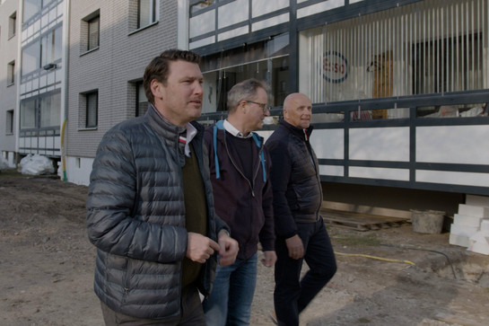 Drei Männer vor einem Wohnhaus