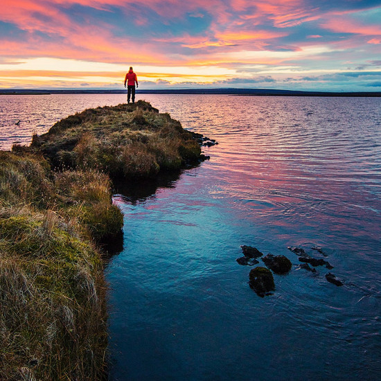 Ein Mann in roter Jacke steht an der Spitze eines Ufers