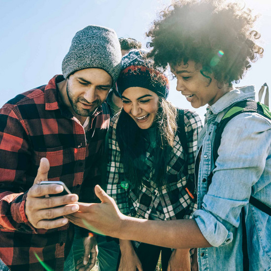 Drei Personen schauen auf Smartphone