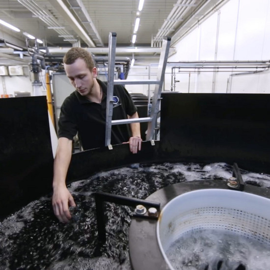 Ein Mann fässt in ein Behälter mit einer Flüssigkeit