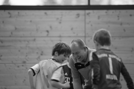 Ein Fußballtrainer lacht mit seiner Mannschaft