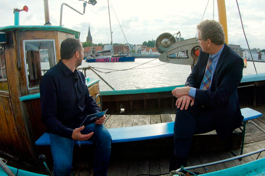 Bernd Buchholz und Timo Klass schauen auf ein vorbeifahrendes Segelboot