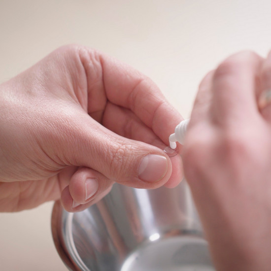 Eine Person tröpfelt Flüssigkeit auf eine Kontaktlinse