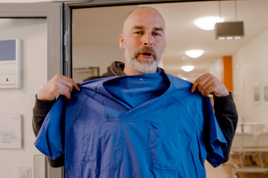 York hält ein blaues Krankenpfleger Shirt hoch