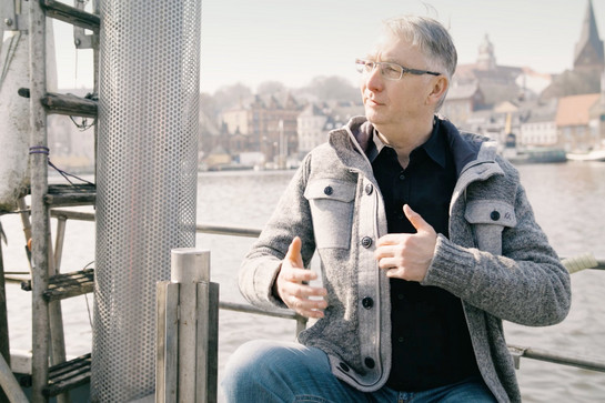 Mann mit grauer Jacke sitzt auf Kutter